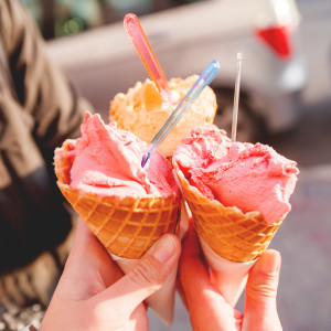 Three colorful tasty ice cream cones in hands.
