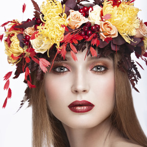 Beautiful red-haired girl with bright autumn wreath of leaves
