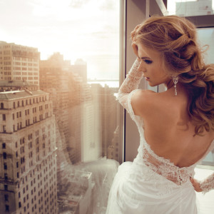 Beautiful Young bride in wedding dress posing near window