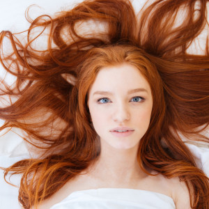 Woman with beautiful long red hair lying in bed