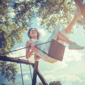 Happy young woman smiling on swing