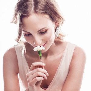 Beautiful young woman smelling a flower