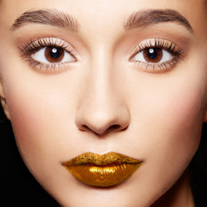 Closeup of woman face.perfect skin, gold lips,long eyelashes.