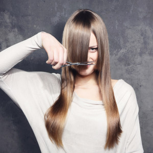 Young woman with scissors trimming her bangs